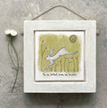 East of India small square whitewashed wooden framed picture of a leaping white hare on a sage green background with wildflower stems, a gold sun circle, and the sentiment "You are brilliant, brave and beautiful," hung with natural jute string.